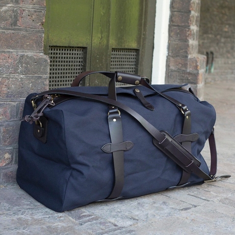 Filson Rugged Twill Duffle Bag Small Navy, a water-resistant, heavy-duty duffle with leather accents that meets airline carry-on size restrictions